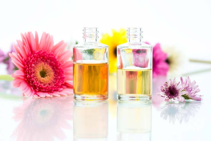 essential oils bottles bright flowers white background
