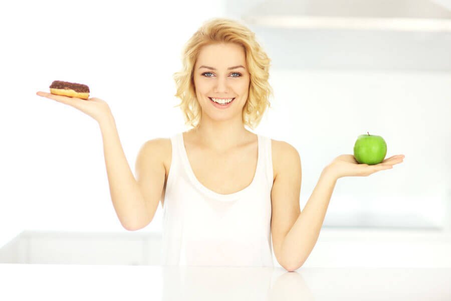 woman holding up unhealthy and healthy food